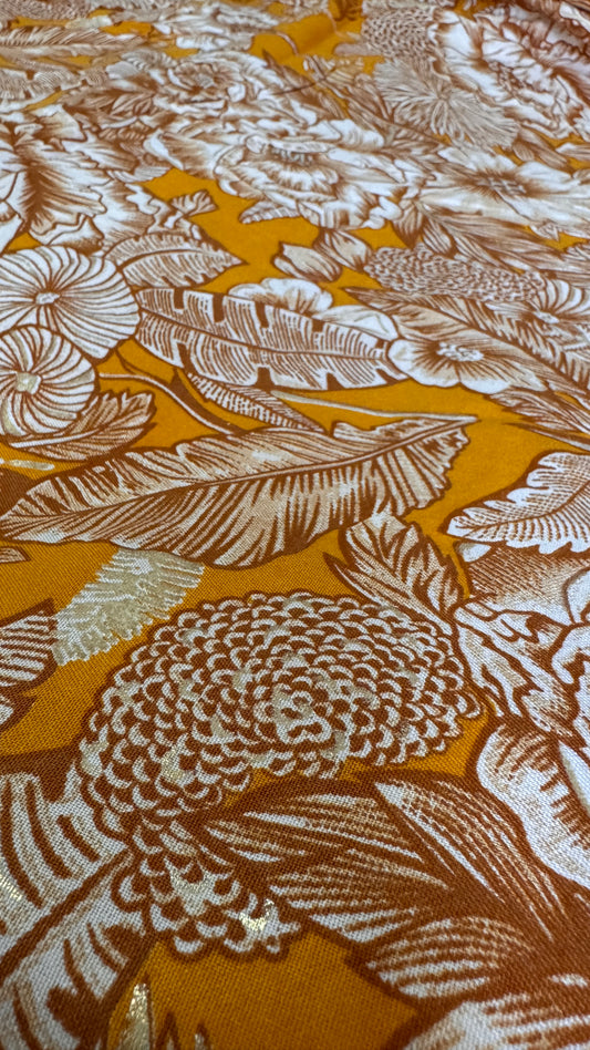 Close-up of floral and leaf pattern fabric with gold and white colors.