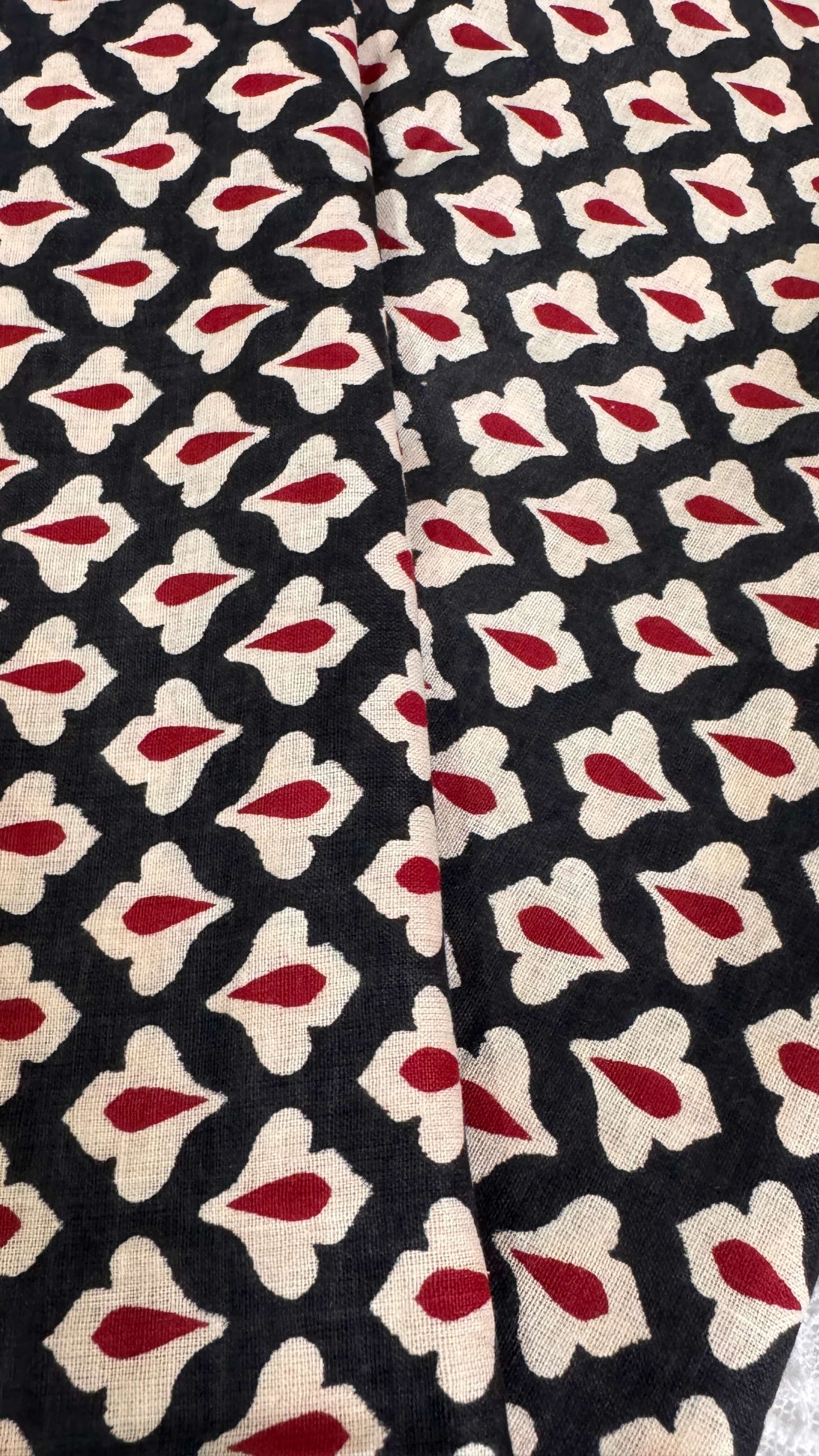 Patterned fabric with red and beige shapes on a black background