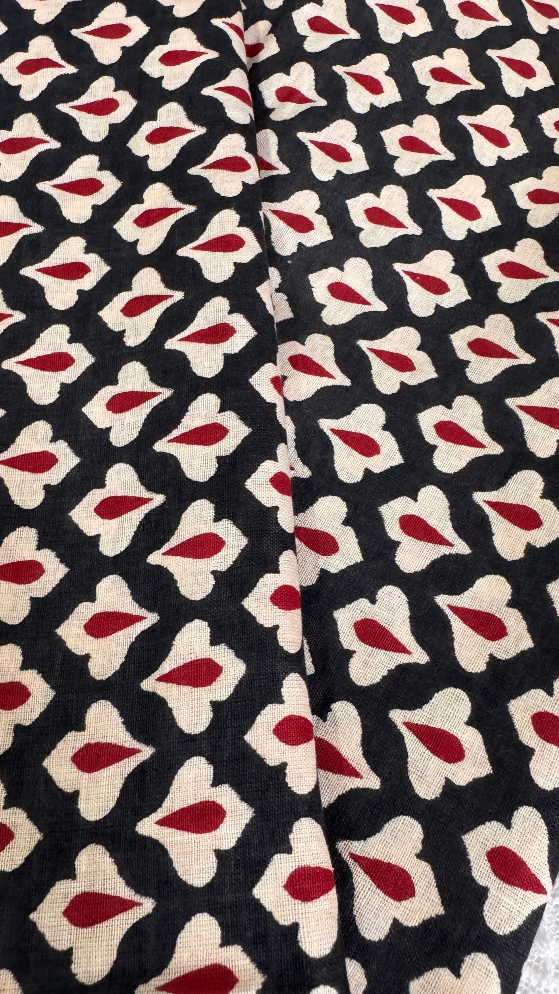 Patterned fabric with red and beige shapes on a black background