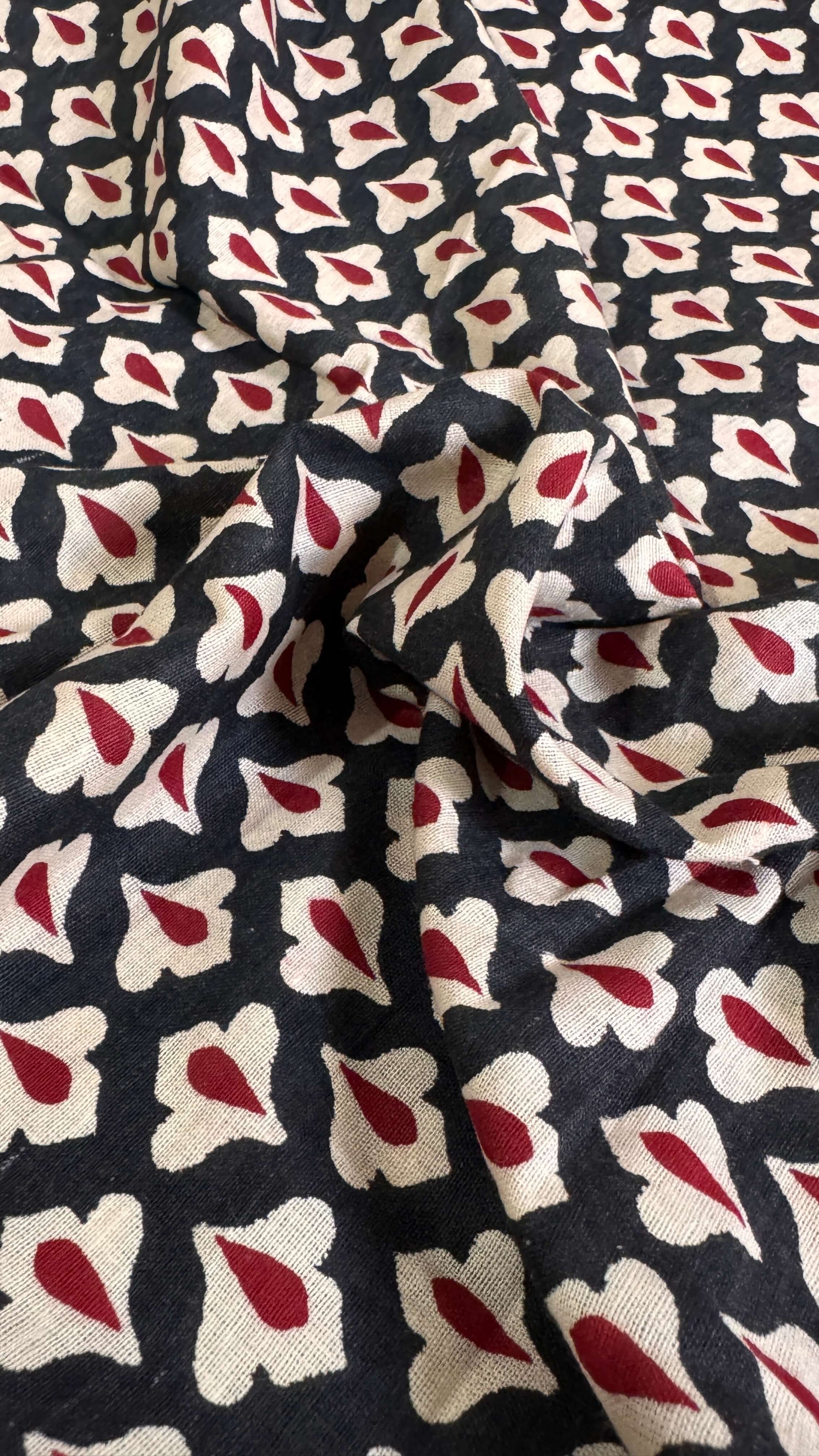 Fabric with a pattern of red and white shapes on a dark background