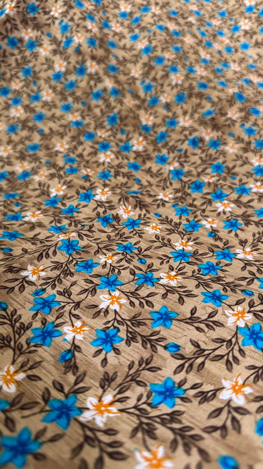 Floral patterned fabric with blue, orange, and white flowers on a brown background