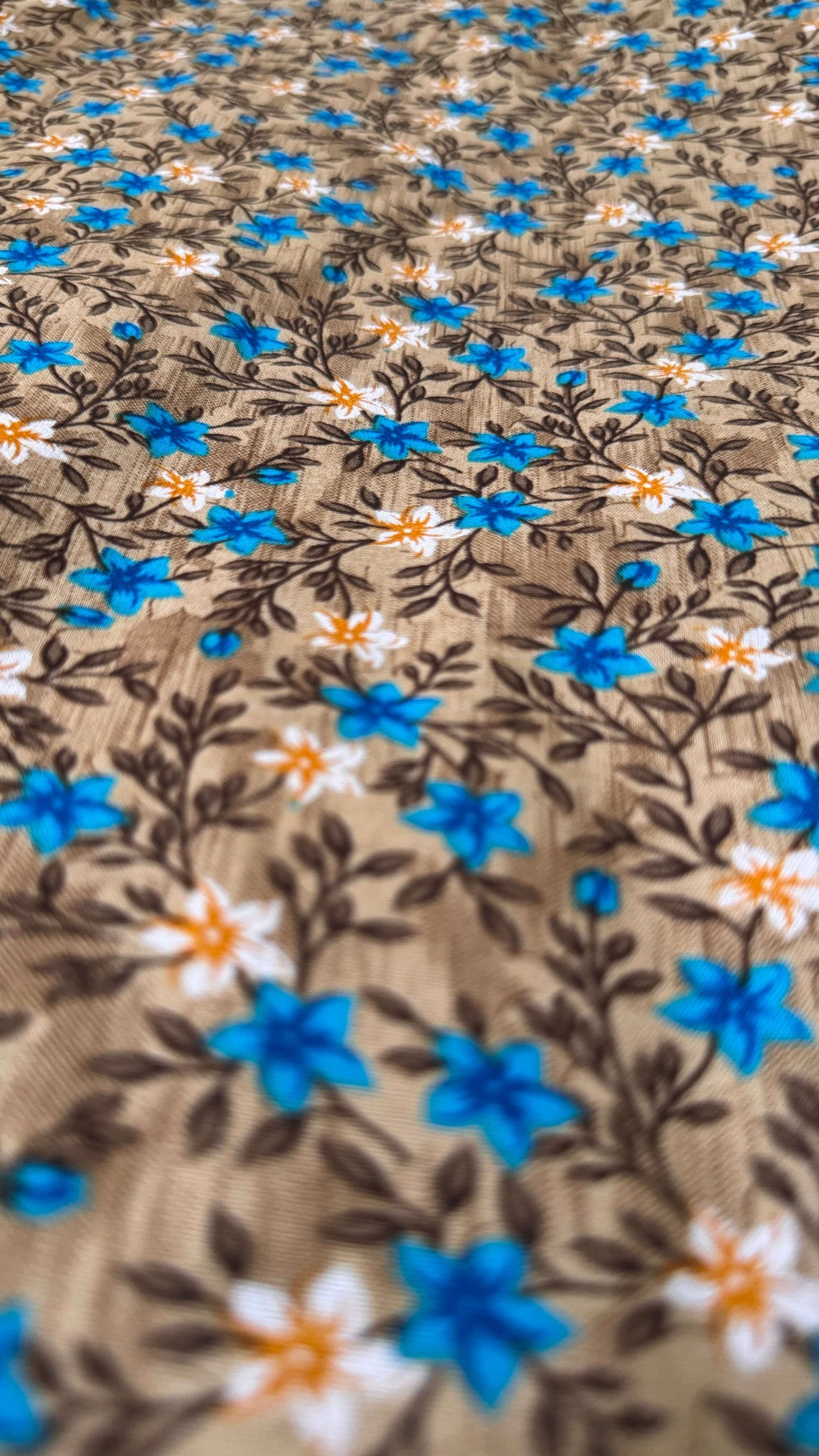 Close-up of fabric with blue and white floral pattern on brown background
