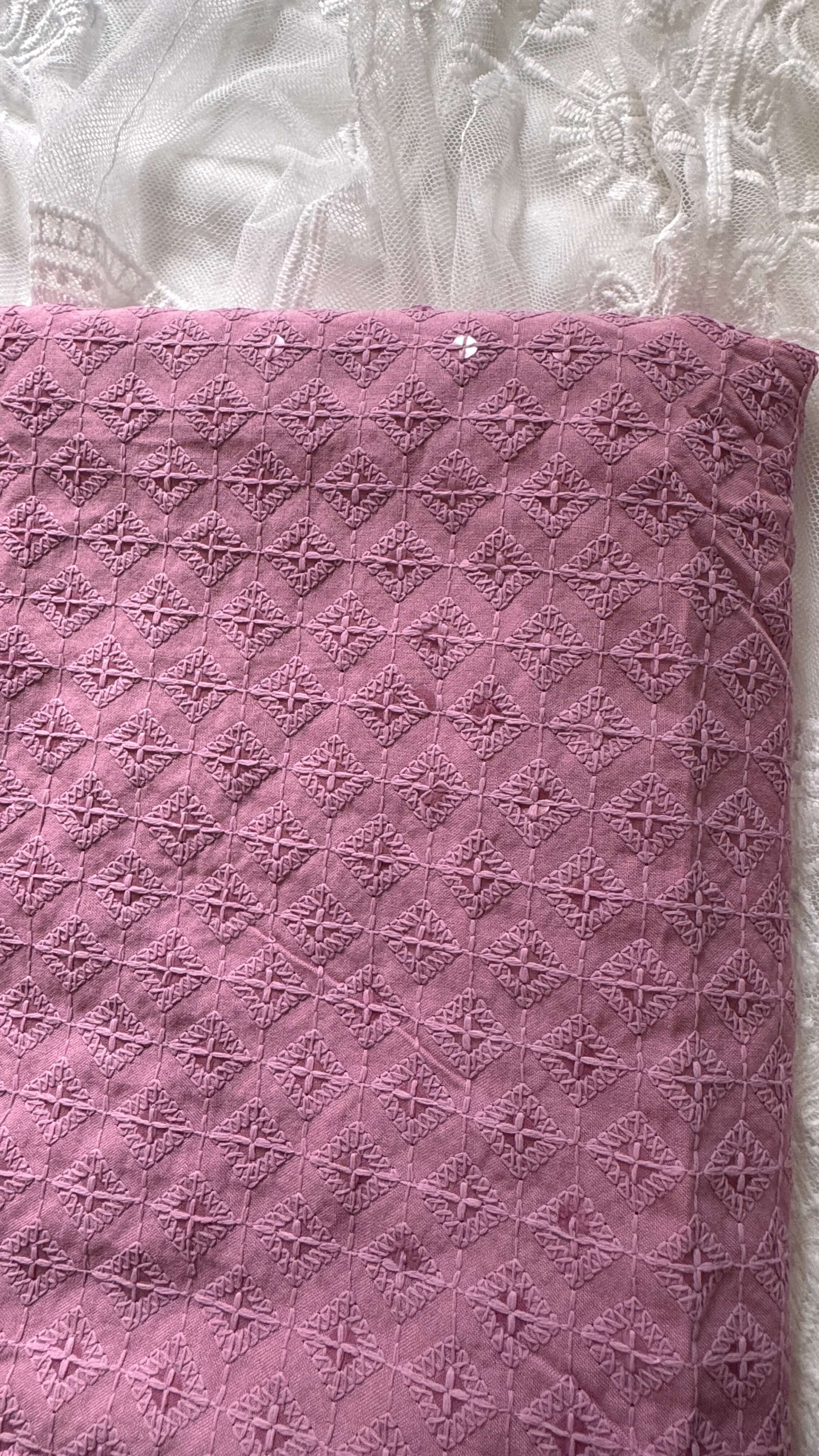 Pink textured fabric with a diamond pattern on a white lace background