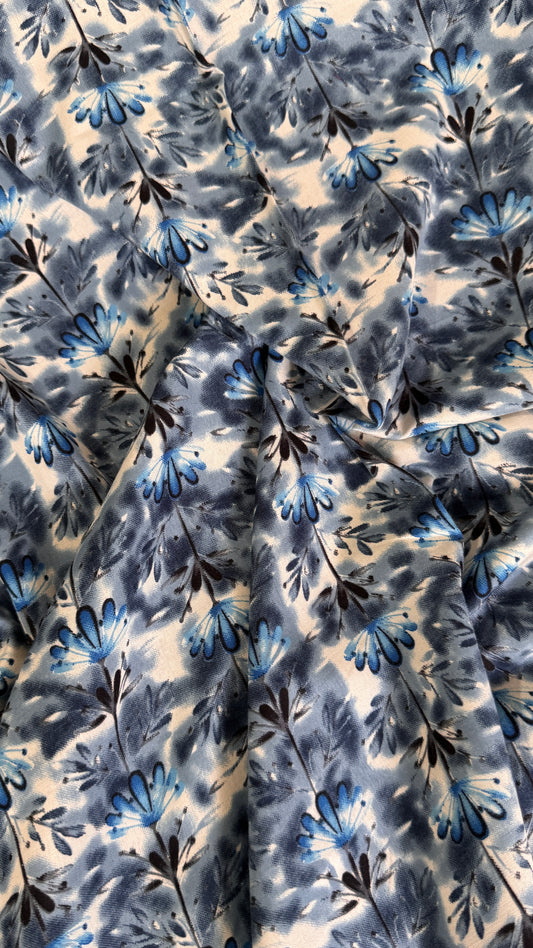 Floral patterned fabric with blue and black flowers on a beige background