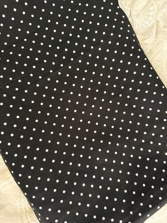 Black fabric with white polka dots on a beige surface
