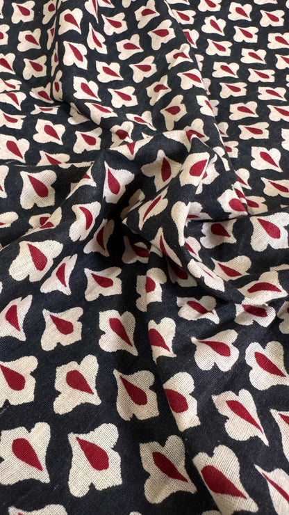 Fabric with a pattern of red and white shapes on a dark background