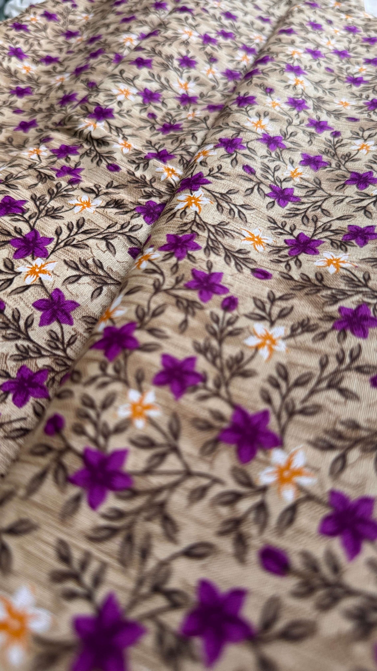 Close-up of fabric with floral pattern featuring purple flowers and orange centers.