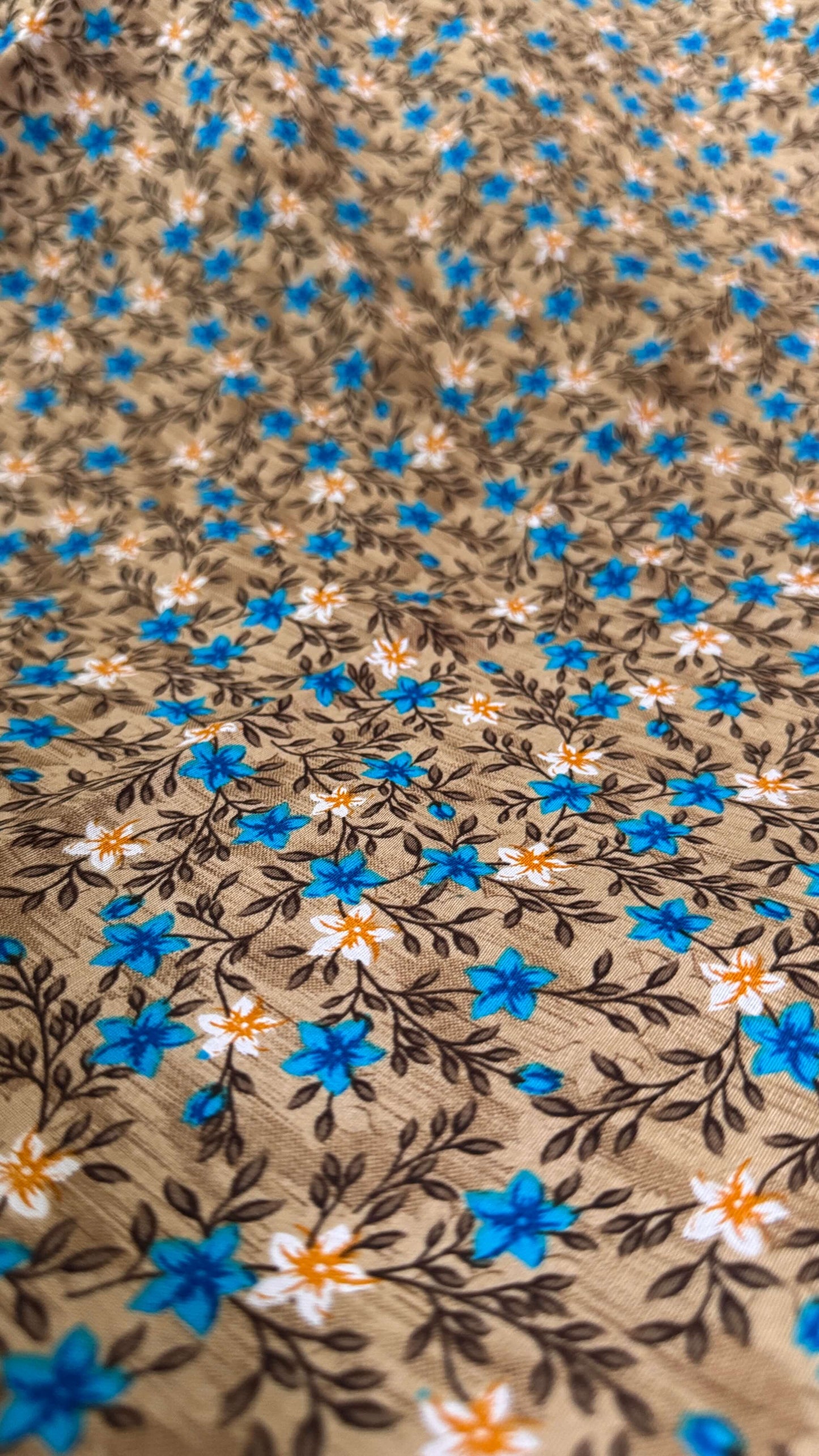 Floral patterned fabric with blue, orange, and white flowers on a brown background
