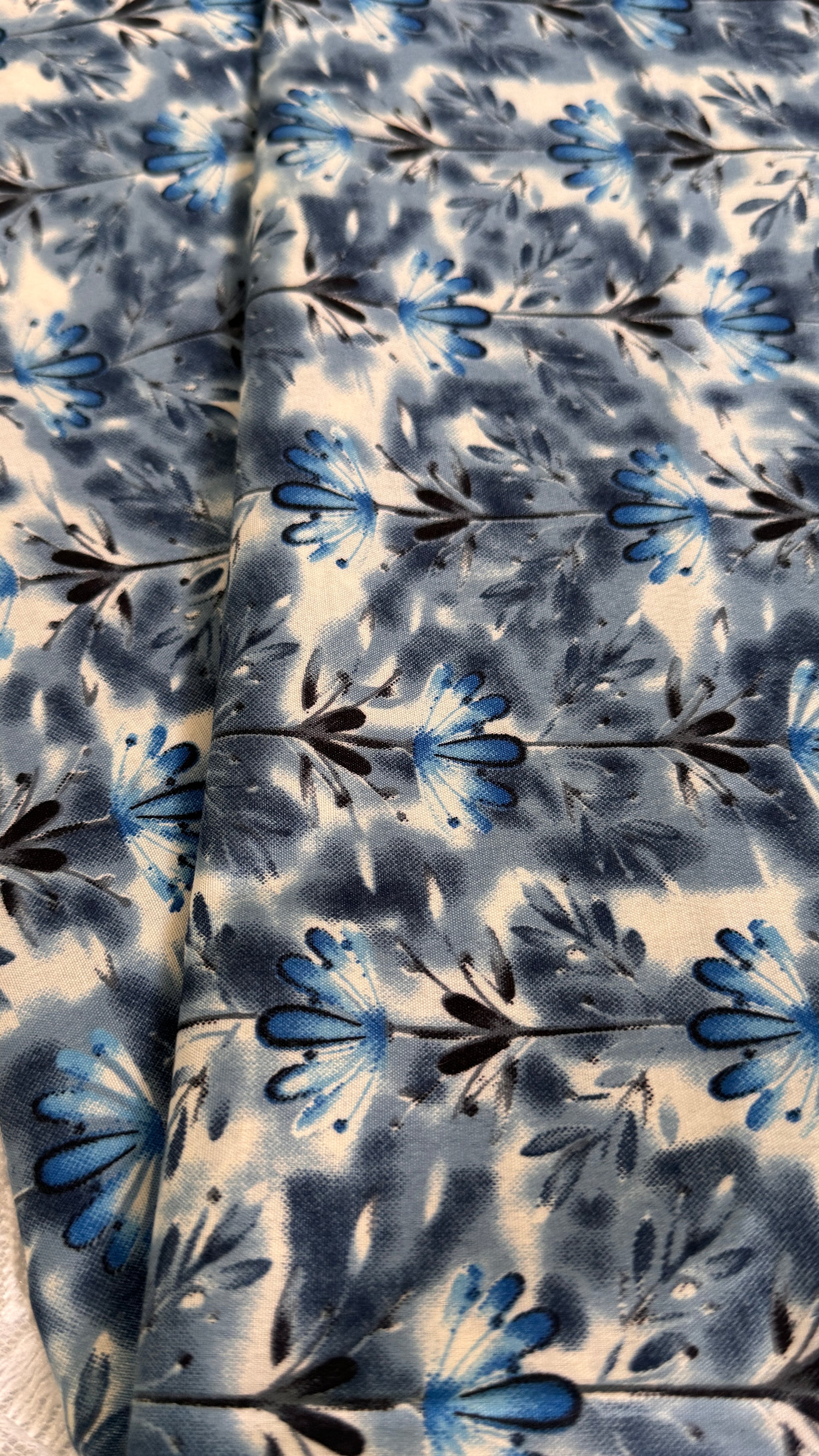 Floral patterned fabric with blue and black flowers on a white background